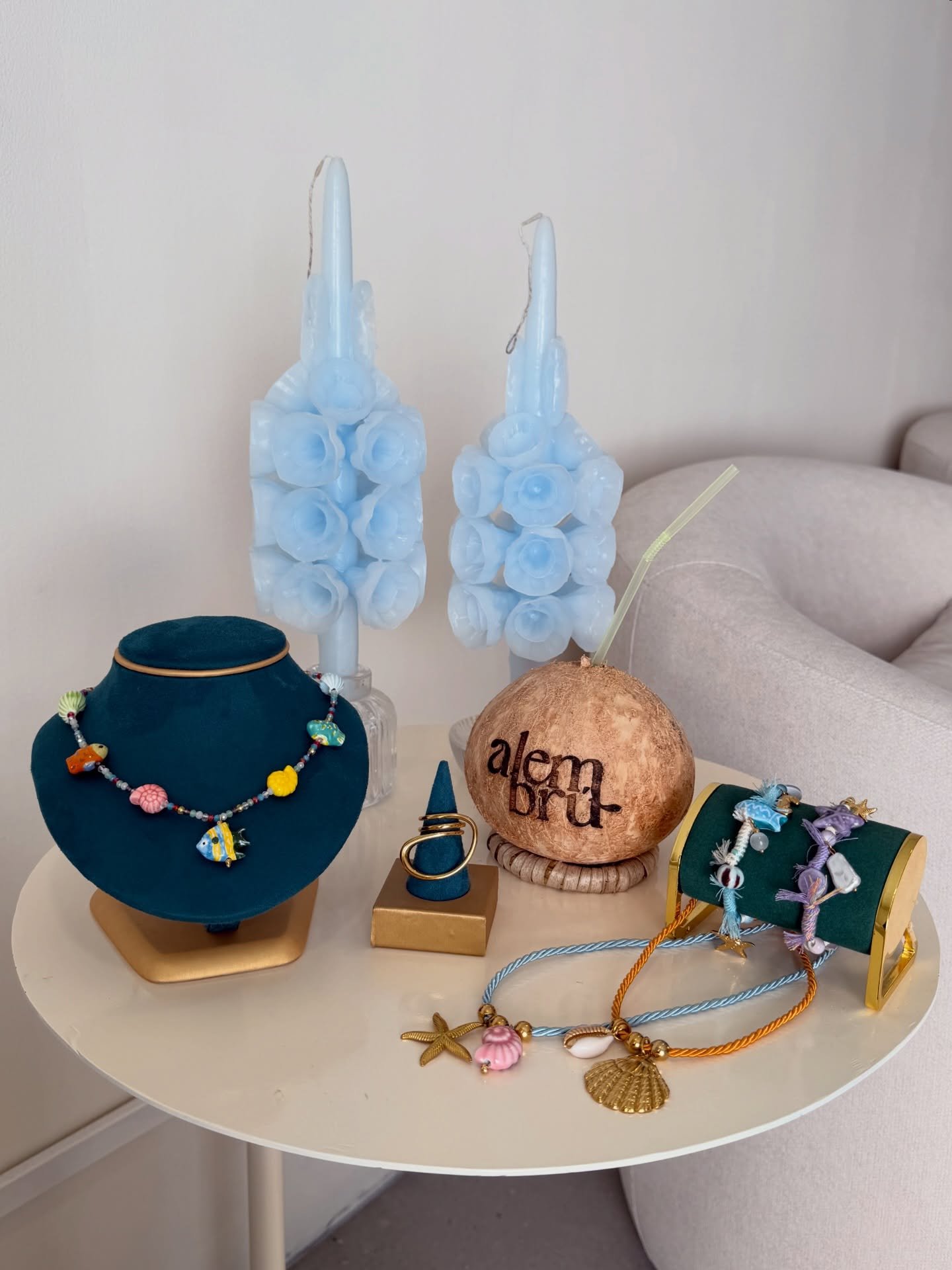 Mesa costera ALAIA: velas de rosa escultural, joyería y copa de coco